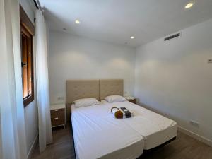 a white bedroom with a bed with a purse on it at Canovas Nerja - Oasis de Capistrano in Nerja +27 photos