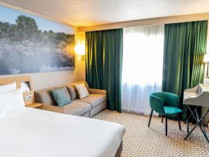 a hotel room with a bed and a couch at Novotel Orléans Chemins De Sologne Demeures De Campagne in Orléans