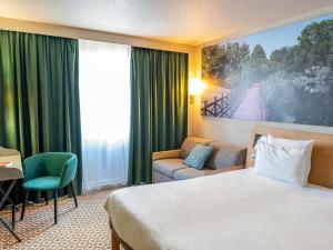 a hotel room with a bed and a couch at Novotel Orléans Chemins De Sologne Demeures De Campagne in Orléans