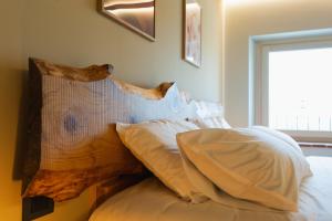 a bed with white pillows and a wooden head board at Corte Bonfiglio Colombari in Illasi