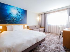 una habitación de hotel con una cama y un escritorio en Novotel Saint Avold, en Saint-Avold 120 fotos más