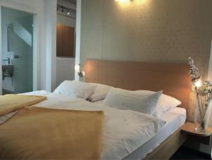 a large bed with white sheets and pillows at Hotel Kurpfalz in Speyer +2 photos