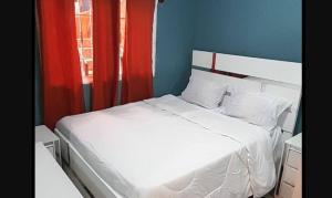 a bedroom with a white bed with red curtains at Don Carlos Recidencia in Camarón
