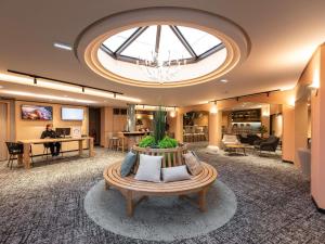 an office lobby with a large skylight and a table at Novotel Macon Nord - Porte de Bourgogne in Mâcon