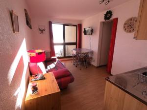 a living room with a red couch and a table at Studio plein sud avec vue magnifique in Château-Bernard