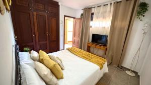 une chambre avec un lit avec des draps blancs et des oreillers jaunes dans l'établissement Bohemio Playa Los Cristianos by Deihu Experiences, à El Guincho