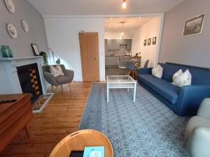 Una sala de estar con un sofá azul y una mesa. en Nos-da, en Menai Bridge 10 fotos más