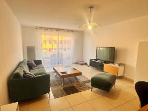 een woonkamer met een bank en een tv bij Appart 2 Chambres Charley super emplacement et parking in Calvi