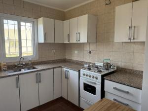 una cucina con mobili bianchi e un forno a piano cottura di Casa Quinta Suipacha a Suipacha Altre 4 foto