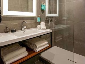 a bathroom with a sink and a shower with towels at Novotel Antwerpen - Ekeren in Antwerp