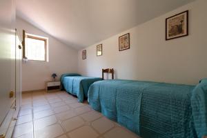 ミントゥルノにあるMontecristoの青い掛け布団付きの客室内のベッド2台
