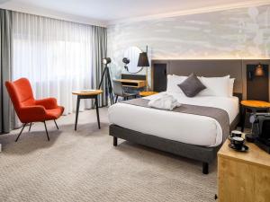 a hotel room with a large bed and a chair at Mercure Bedford Centre Hotel in Bedford