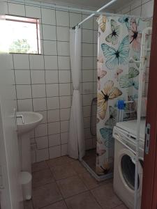 a bathroom with a shower curtain and a washing machine at Lit simple en chambre partagée au Domaine de Baradoz in La Plaine des Palmistes