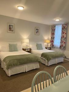 a bedroom with two beds and two chairs at Birch Lane Guesthouse in Wexford