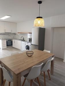 a kitchen with a wooden table and white chairs at T3 São Martinho do Porto in São Martinho do Porto