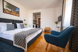 ein Schlafzimmer mit einem Bett und einem blauen Stuhl in der Unterkunft Grossmann Ház in Mád