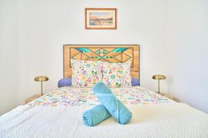 a bed with a pair of blue slippers on it at Namasté - Idéal familles - Terrasse - Garage - Mer in Six-Fours-les-Plages