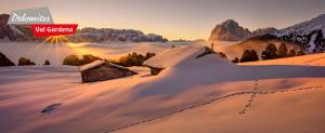 a winter scene with a wooden cabin in the snow at Dumbria Dolomites in Selva di Val Gardena