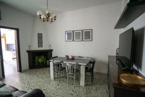 Una sala de estar con una mesa y sillas y un televisor. en Casa Scano, 