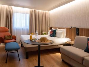 a hotel room with a bed and a table and chairs at Novotel Nice Arenas Aeroport in Nice