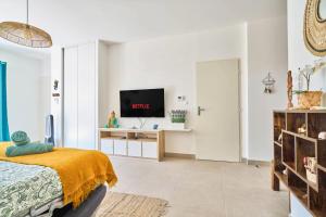 a white room with a bed and a tv at Namasté - Idéal familles - Terrasse - Garage - Mer in Six-Fours-les-Plages