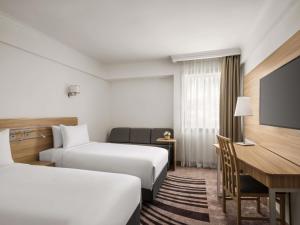 a hotel room with two beds and a desk at Novotel Cairo Airport in Cairo