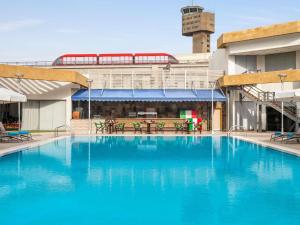 a large blue swimming pool in front of a building at Novotel Cairo Airport in Cairo