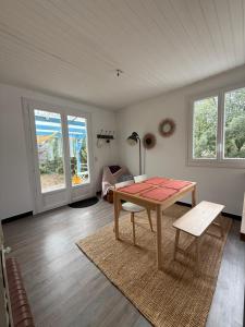 Una sala de estar con mesa y sillas y ventanas. en L’Albizia, en La Tranche-sur-Mer