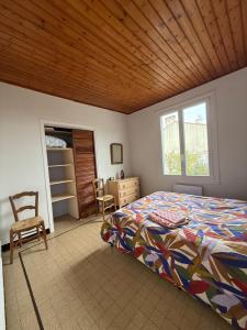 Un dormitorio con una cama y un techo de madera. en L’Albizia, en La Tranche-sur-Mer