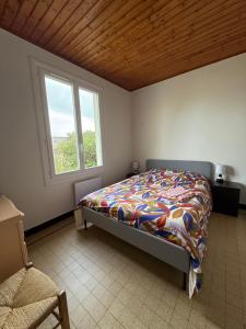 Un dormitorio con una cama con edredón y una ventana. en L’Albizia, en La Tranche-sur-Mer 2 fotos más
