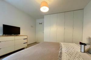 a bedroom with a bed and a tv on a dresser at PULLY LAUSANNE sunny apartment on lakeside street and direct bus to Lausanne train station in Pully