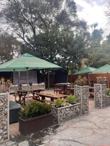 Un patio con mesas, sillas y sombrillas. en Masana Hotels, en Polokwane