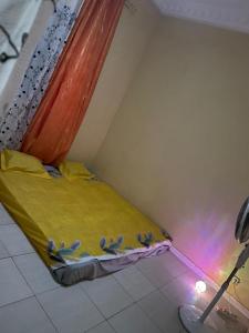 a small bedroom with a bed with yellow sheets and birds on it at Logement Salam in Dakar