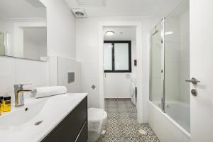 a bathroom with a sink and a tub and a toilet at O&O Group-Charming 4BR APT with Stellar Sea View in Bat Yam