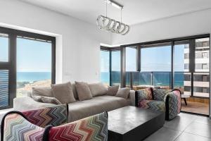 a living room with a couch and some windows at O&O Group-Charming 4BR APT with Stellar Sea View in Bat Yam