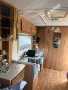 a man in an rv with a laptop on a desk at Beach Bum Caravan in Caparica
