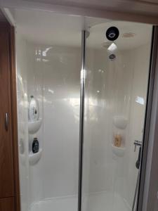 a shower with a glass door in a bathroom at Beach Bum Caravan in Caparica
