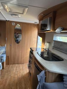 a kitchen in an rv with a sink and a mirror at Beach Bum Caravan in Caparica