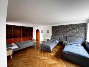 a bedroom with three beds and a stone wall at Vardi Haus in Ingolstadt