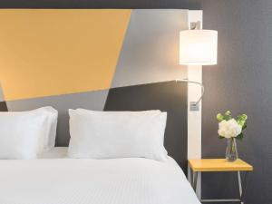 a bedroom with a white bed and a yellow and gray wall at Pullman Toulouse in Blagnac