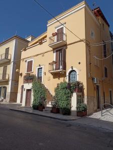 un edificio amarillo con plantas al lado de una calle en B&B Il Principe, en Palo del Colle
