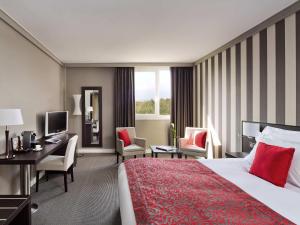 a hotel room with a bed and a desk at Pullman Toulouse in Blagnac