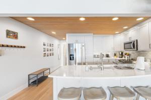 a kitchen with a large white counter and stools at Lake Chelan Shores - Beachfront Sunsets #6-5 in Chelan +43 photos