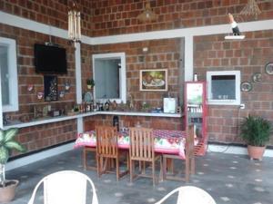 a patio with a table and chairs and a television at Brisa da Serra Pousada EM SOBRAL-CE in Sobral