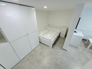 Cette chambre blanche comprend un lit et un bureau. dans l'établissement Krásny byt - apartmán 6 v blízkosti centra, à Bratislava