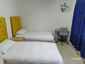 une chambre avec deux lits et un bureau avec une chaise dans l'établissement Royal Inn - Fully Furnished Self-Catering Apartments, à Lenasia