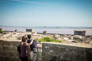 a man and woman standing on a wall looking at a city at Chez Elsa et Camille in Aigues-Mortes +5 photos