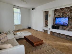 a living room with a couch and a tv on a brick wall at Workhouse - 6 couchages in Wasquehal