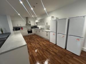 a large kitchen with white appliances and wooden floors at Lovely room in derby in Derby