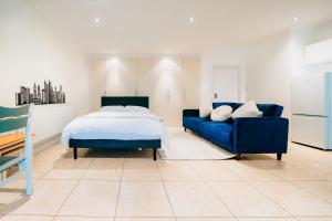 - une chambre avec un lit bleu et un canapé bleu dans l'établissement Bright & Comfy 3-BR House in Feltham and a Separate Studio - Sleeps 11!, à New Bedfont